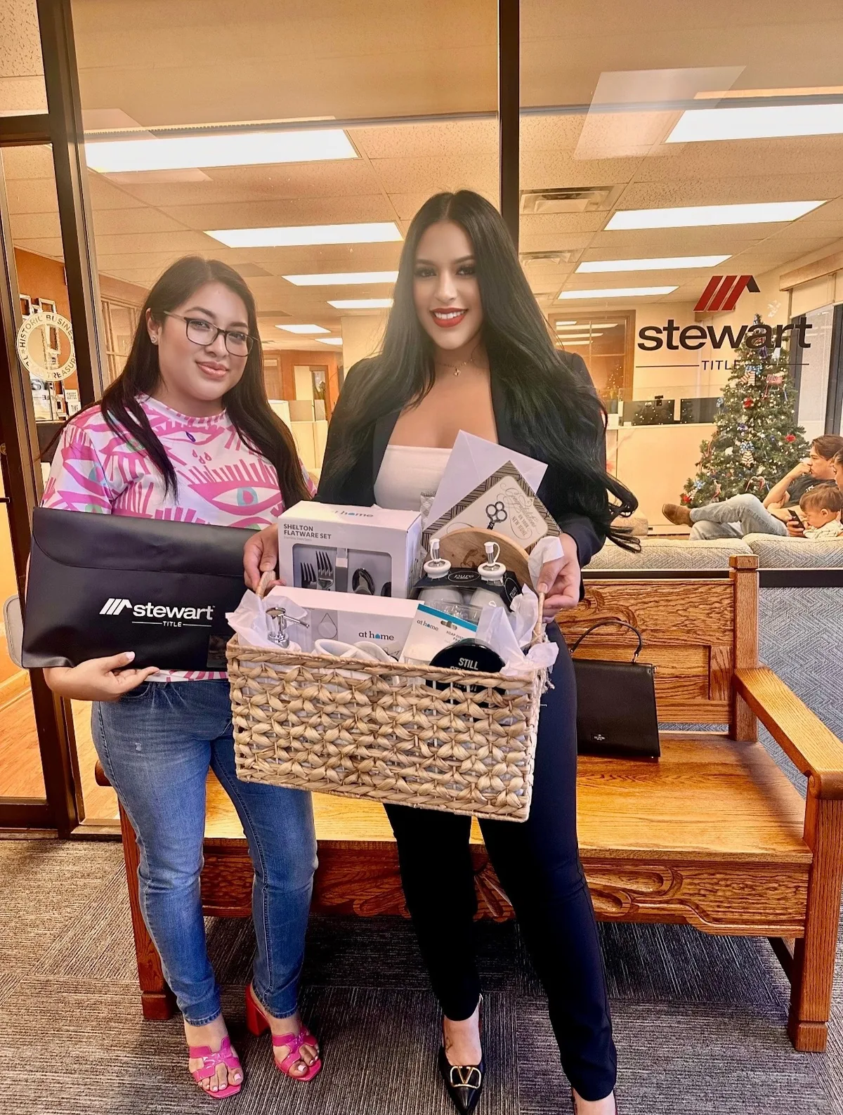 Daisy Luna with a Reliable Credit Solutions client on closing day at Stewart Title in El Paso, holding a closing gift basket.